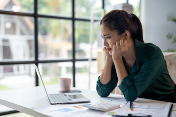 A woman is sitting at a desk with a laptop and a calculator