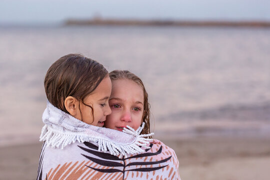 First Nations Australian girls feeling cold and wrapped in a towel after swimming at the beach