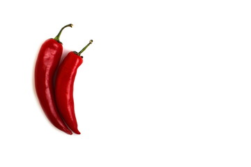 Two red hot peppers lie on a white background.	