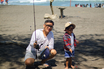 Happy father, fishing and lesson with son on rock with rod by lake, ocean or beach together in...