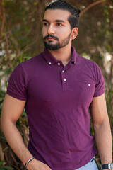 Close-up portrait of a confident, handsome, bearded Asian-Indian man with a ponytail. He's gazing...