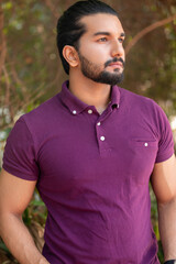 Close-up portrait of a confident, handsome, bearded Asian-Indian man with a ponytail. He's gazing...