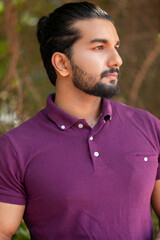 Close-up portrait of a confident, handsome, bearded Asian-Indian man with a ponytail. He's gazing...