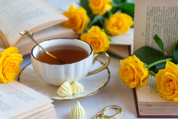 On the white table there is hot tea, cakes and delicate roses.