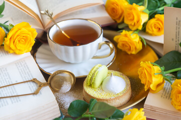On the white table there is hot tea, cakes and delicate roses.