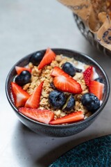 Bowl of crunchy granola topped with fresh blueberries and strawberries for a healthy breakfast
