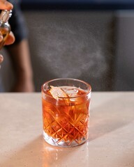 Bartender spraying on cocktail garnish with atomizer in bar setting