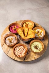Variety of colorful dips with tortilla chips on wooden tray