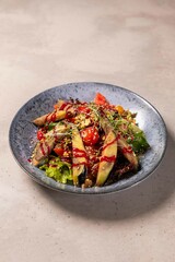 Grilled eggplant salad with tomatoes and walnuts sitting on plate