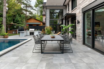 Grey porcelain pavers creating an elegant outdoor dining area near a swimming pool and house.