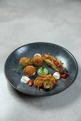 Gourmet vegan meal with eggplant, croquettes, and avocado cream being served on a plate