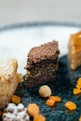 Chocolate covered baklava laying on a plate with assorted nuts and candied fruit