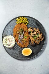 Breaded chicken cutlet being served with sauteed mushrooms and peas