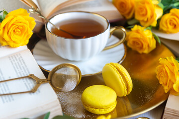 On the white table there is hot tea, cakes and delicate roses.