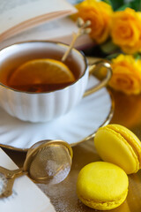 On the white table there is hot tea, cakes and delicate roses.
