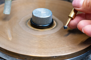 Close-up view of the faceting of the round blue sapphire on the metal cutting lap.