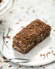 Chocolate cake sitting on a white plate covered in chocolate shavings