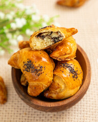 Mini croissants with poppy seeds overflowing a wooden bowl