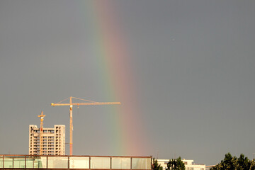 rainbow over the city with tower crane and skyscraper in the background