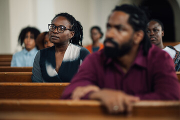 Group of churchgoers sitting in pews listening to sermon