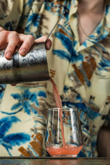 Bartender pouring a cocktail from a mixing glass into a rocks glass