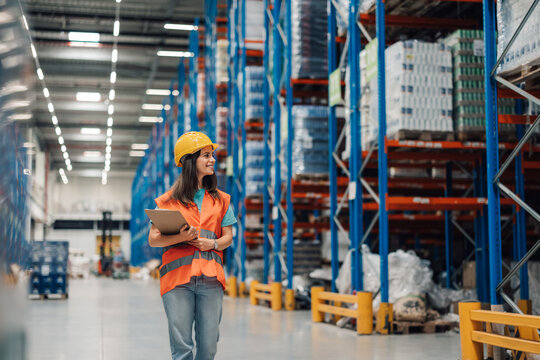 Female warehouse worker holding clipboard doing inventory in logistics center