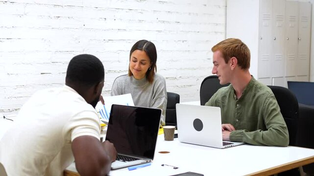 Multiracial people working using laptop in a modern coworking space with shared tables