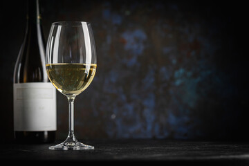 A dark, elegant still life of white wine in a glass with wooden background. Perfect for wine-themed compositions