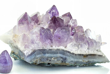 Close-up of a raw amethyst geode crystal with purple and clear quartz formations, isolated on a...