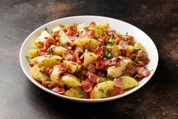 German Potato Salad with bacon and herbs in a white plate