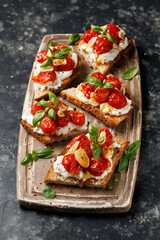 Cottage cheese and roasted tomatoes sourdough bread toast on a wooden board.
