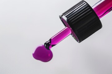 Discover the elegance of fuchsia purple serum oil with a sleek dropper against a soft gray backdrop