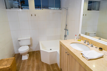 baño de departamento iluminado con lavabo , inodoro y  tina para baño