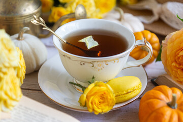 Cup of tea with orange and small pumpkins on white table, September.