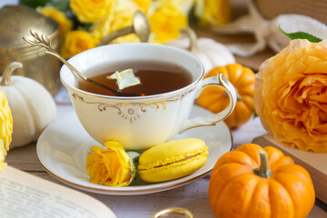 Cup of tea with orange and small pumpkins on white table, September.