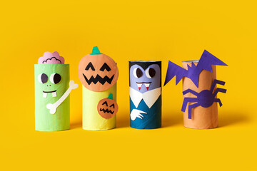 Halloween monsters from toilet paper roll tube, easy DIY handmade decorations idea. Spooky paper toys on yellow background. Kids creativity concept. easy eco craft, step by step, place for text