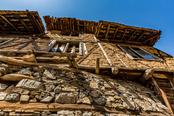 Abandoned houses and other buildings, lit by sunlight, street view, Pirin village and mountain, Bulgaria