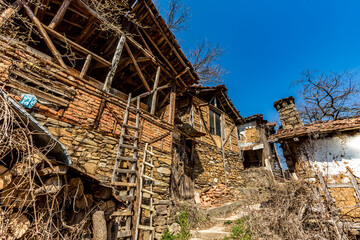 Abandoned houses and other buildings, lit by sunlight, street view, Pirin village and mountain, Bulgaria