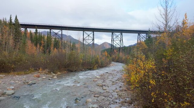 Dolly Across Alaskan Creek in Autumn with Train Trestle Bridge