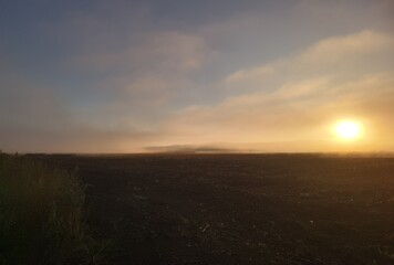 Obraz premium Morning sun through foggy field. Colorful sunrise 