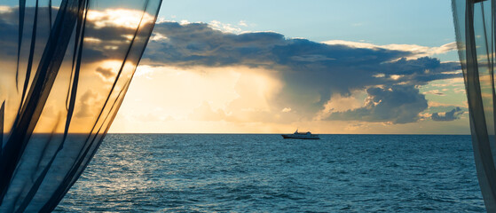 Obraz premium Beautiful sunset landscape of a ship on the sea with a view from behind the curtains. Panorama.