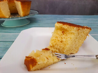 Yogurt cake with a spatula on a wooden table, top view.