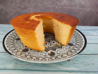 Yogurt cake with a spatula on a wooden table, top view.