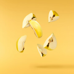 Fresh ripe yellow Quince fruit  falling in the air isolated on yellow background. Food levitation...