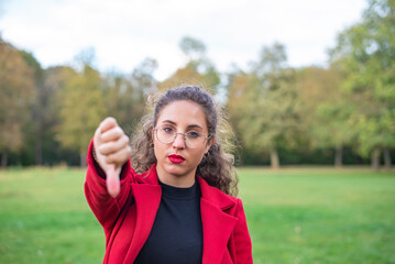  junge Frau zeigt Daumen runter im herbstlichen Park