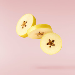 Fresh ripe yellow Quince fruit  falling in the air isolated on pink background. Food levitation or...
