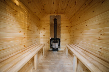 Wooden sauna interior with benches and a heating stove, perfect for relaxation and wellness