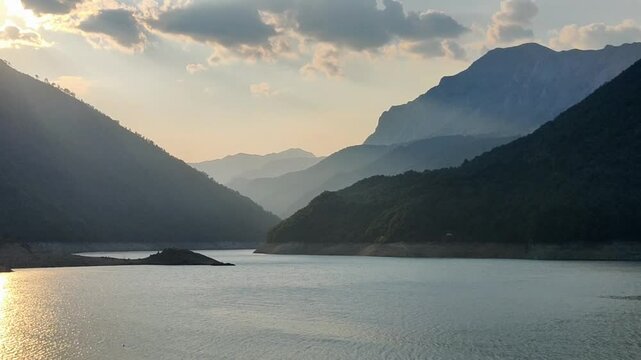 View on Piva river in Pluzhine, Montenegro. Sunset on water. Fog in mountains, haze, mist. Evening summer sunset on hills.