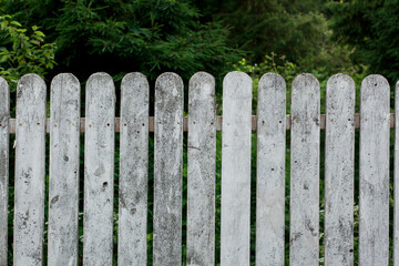 White wooden fence on the green summer garden forest background. front view