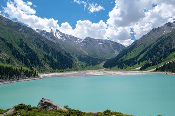 Panorama of Big Almaty Lake in the mountains in summer. Beautiful high-mountain lake not far from Almaty.